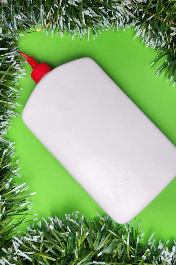 white glue for christmas craft on green background