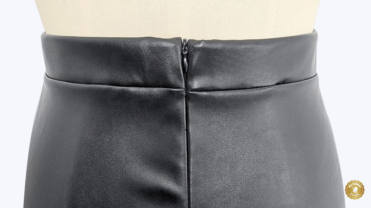 close up of a black leather skirt featuring the waistband and a zipper