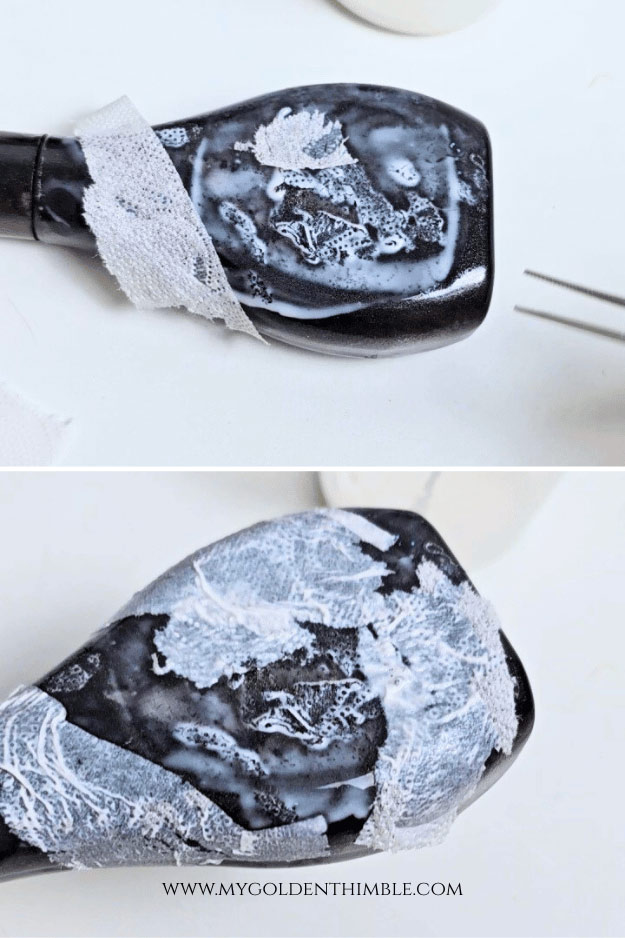 Close-up of a bottle being textured with glue and tissue paper to achieve an aged, vintage potion bottle look.