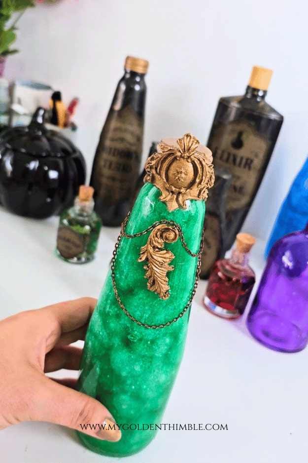 Creating decorative golden flourishes with hot glue and spray paint to embellish potion bottles.