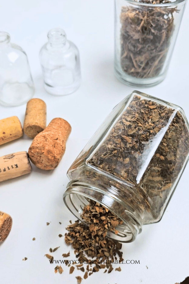 Craft materials for DIY potion bottles including recycled bottles, paint, glitter, corks, branches, and printable potion labels.