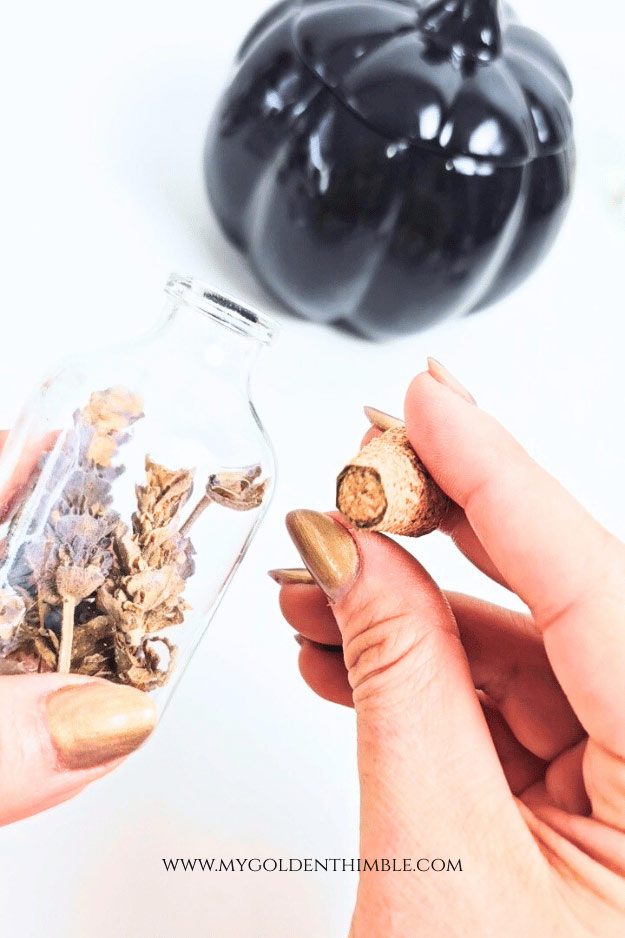hands holding a small bottle and a cork