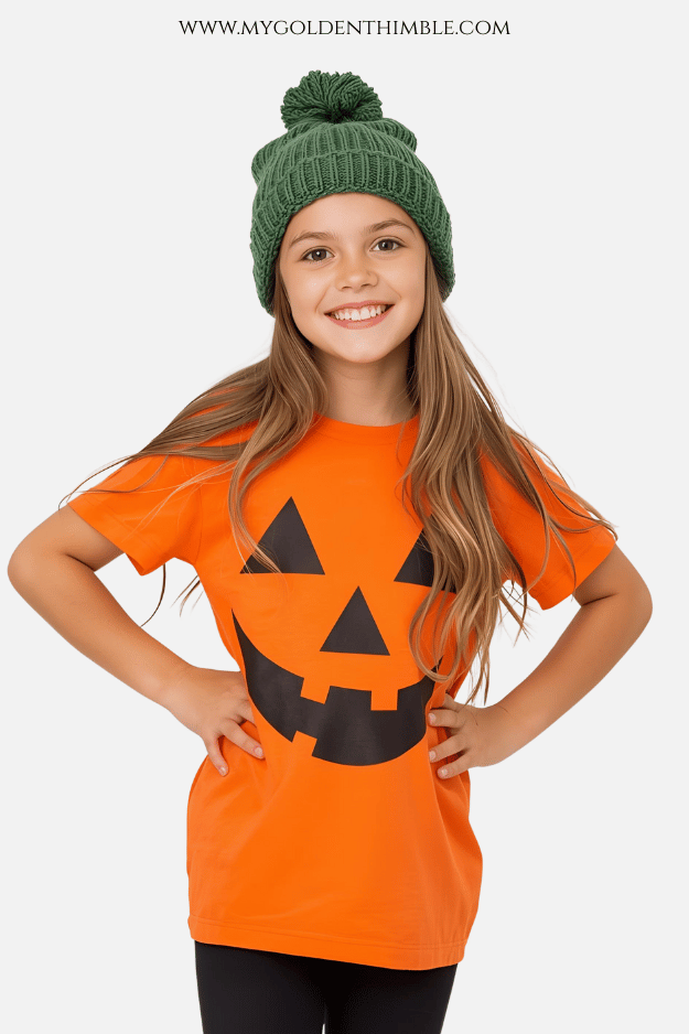 little girl wearing an orange t-shirt with a jack o lantern face