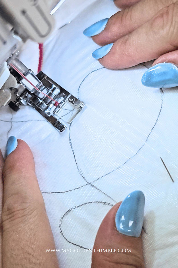 Close-up of needle centered exactly on the traced pencil line while stitching the name onto the cuff.