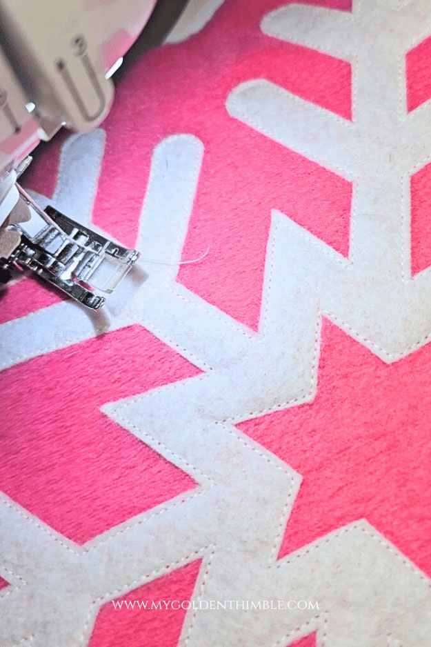 Close-up view of sewing machine stitching the snowflake shape onto the center panel