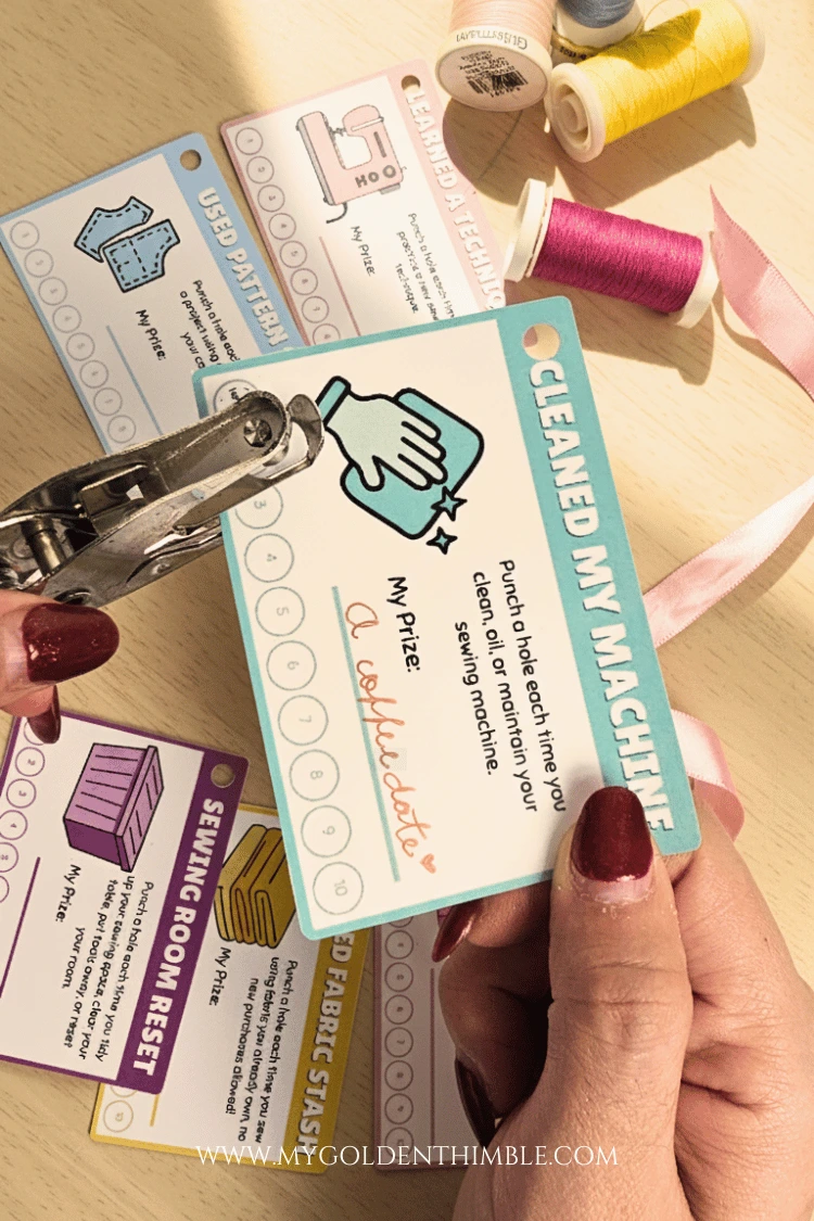 Motivational sewing punch cards resting on a craft table with threads placed around for decoration.