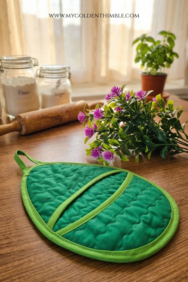 Easter egg potholder sewn with colorful fabric resting on a wooden kitchen table – free sewing pattern project