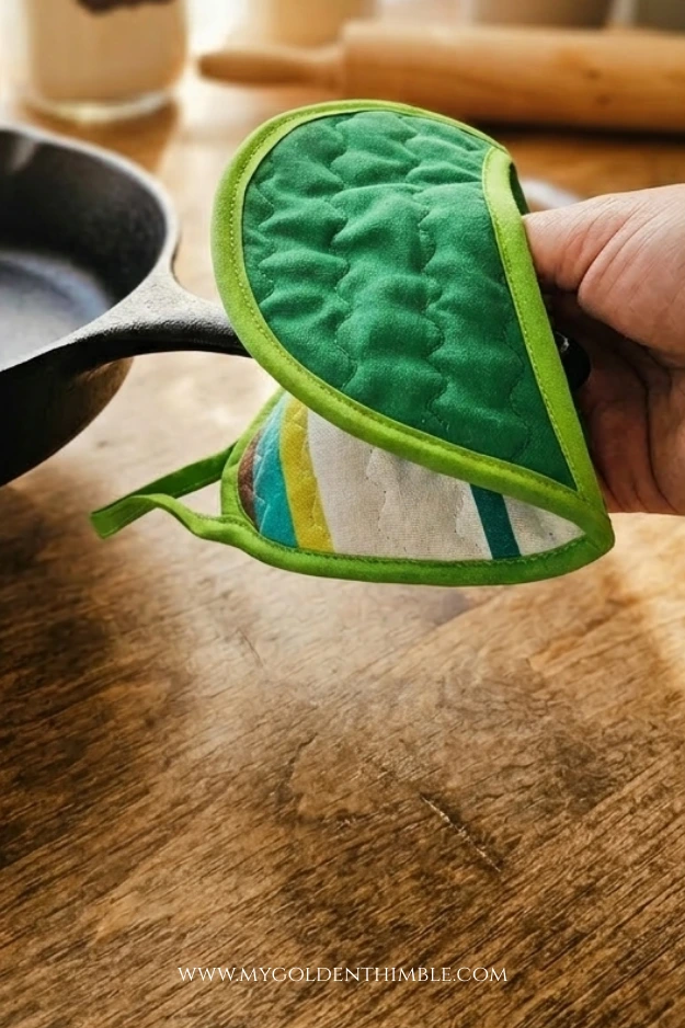 Finished Easter potholder sewing pattern project holding a pan photographed on a wooden kitchen table with soft natural light