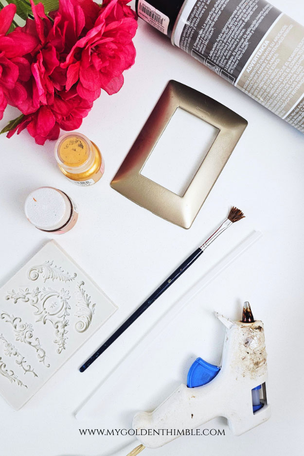 Materials for antique light switch cover DIY including molds, paint, and glue gun