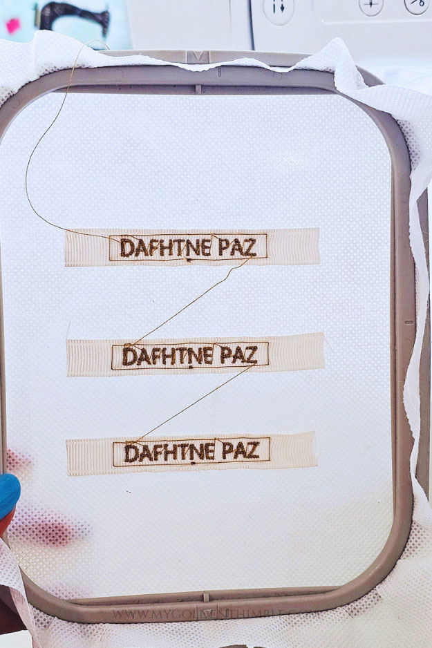 Finished personalized fabric labels still attached to stabilizer in embroidery hoop