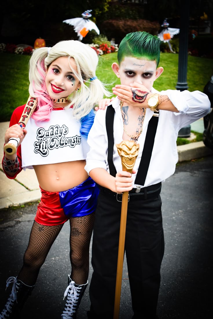 Two individuals dressed in costumes. The person on the left is wearing a green suit with a white face paint resembling the Joker, while the person on the right is dressed in a red and green outfit with long hair, resembling Poison Ivy. Halloween costume ideas