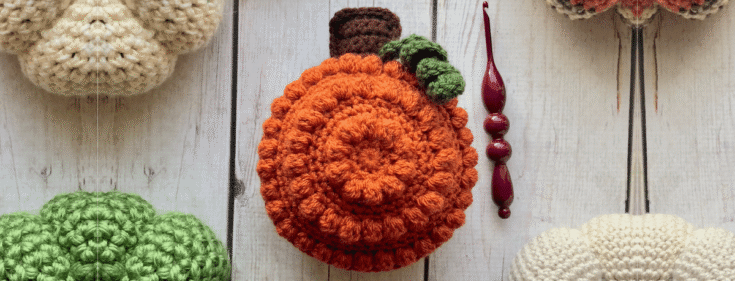 Orange crochet pumpkin with a green stem and brown handle