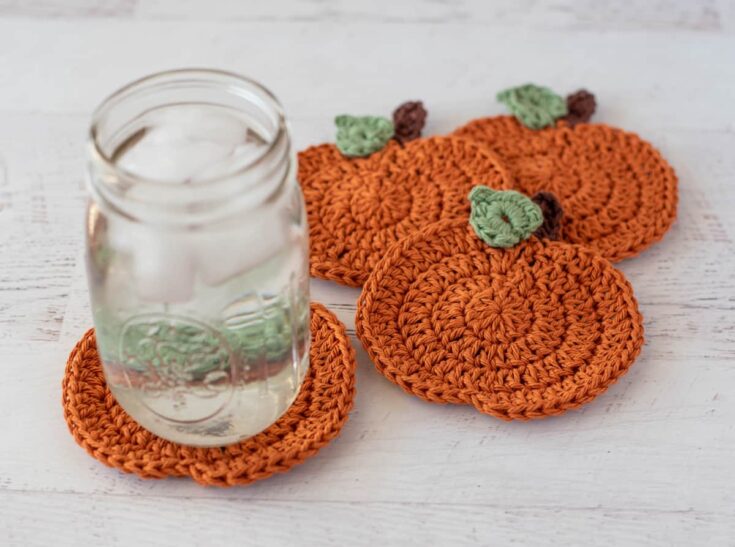 Orange crochet pumpkin coasters with green stems